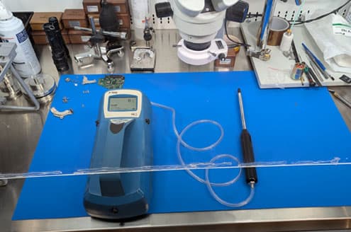 TSI P‑Trak particle counter on the bench with laminar sheet